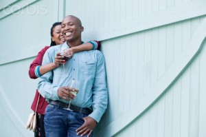 African-american heterosexual couple standing and embracing against wood wall
